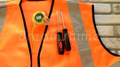 橙色施工背心上有螺丝刀、施工工具、量尺、扳手、劳动节概念